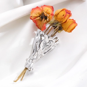 Macro detail of artistic silver flower bouquet brooch with dried roses on silk