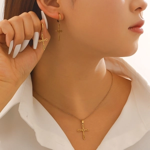 Minimalist gold cross necklace and hoop earring jewelry set worn by a female model