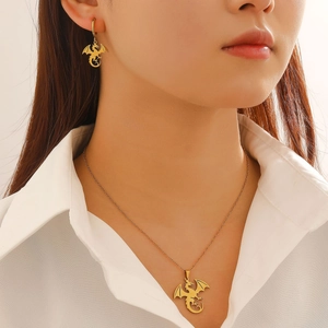 Gothic gold dragon necklace and earring set worn by a model on a white shirt