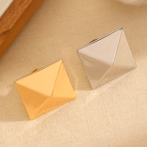 Macro shot of gold and silver pyramid stud earrings with a polished mirror finish