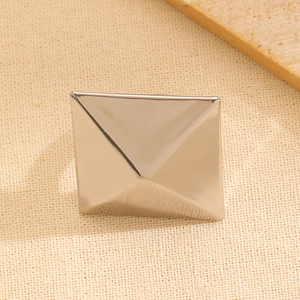 Macro detail of high-polish silver geometric square ring on textured fabric background