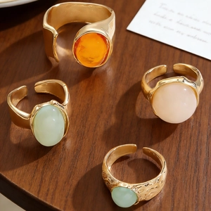 Detailaufnahme des goldenen Ringsets mit bunten Kunststeinen auf dunklem Holzhintergrund