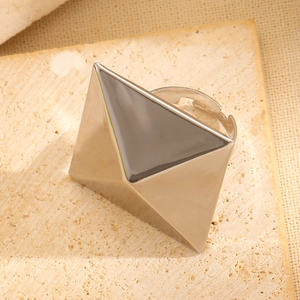 Macro shot of silver geometric pyramid ring on textured stone display stand