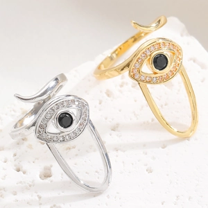 Macro shot of evil eye adjustable rings with black zircon inlay on stone surface