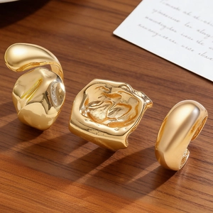 Detail von drei unregelmäßigen Goldringen im Liquid-Metal-Design auf Holzoberfläche