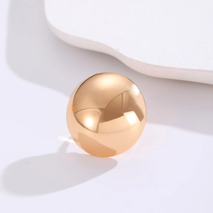 Macro detail of high-polish gold geometric sphere ring on a minimalist stone texture