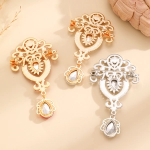 Detailed view of vintage alloy brooches with intricate hollow carving and crystal drop