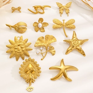 Flat lay of gold stainless steel brooches with butterfly, flower and sun motif designs