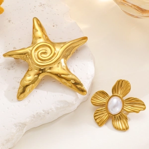 Macro shot of gold starfish and floral brooch with pearl detail on a stone plate