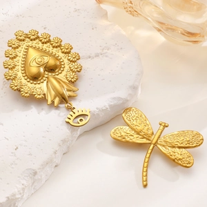 Detail view of heart-shaped brooch with eye motif and golden dragonfly on white stones