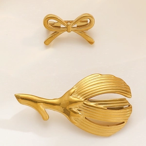 Detailed macro view of matte gold bow and leaf brooch with brushed texture on metal surface