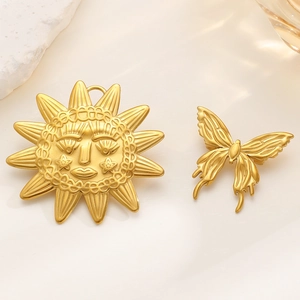 Macro detail of vintage gold butterfly brooch and sun face pendant on stone decor