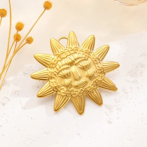 Close-up of golden sun face pendant with matte metal finish and detailed ray pattern
