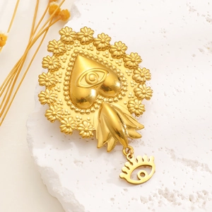 Detail of a vintage golden stainless steel heart brooch with eye symbol and daisy trim