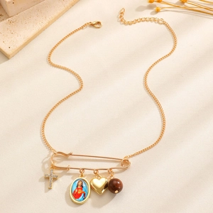 Detailaufnahme der Vintage-Goldanhänger mit Kreuz, Herz und Porträt an einer Sicherheitsnadel