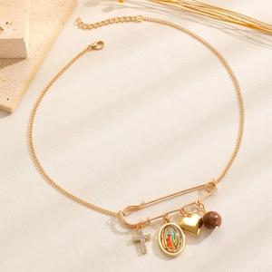 Detailansicht einer Goldkette mit Herz, Kreuz und Marienanhänger an einem Nadelanhänger