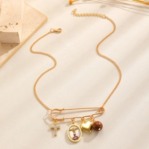 Nahaufnahme der goldenen Vintage-Sicherheitsnadel mit Herz, Kreuz und Porträtanhänger