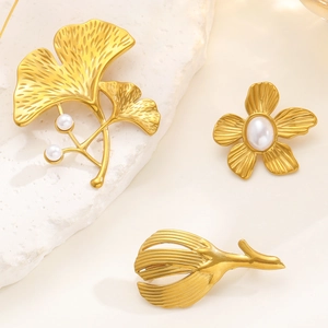 Detailed macro view of vintage gold ginkgo leaf and floral brooches with elegant pearls