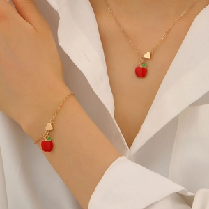 Set di gioielli dorati con ciondoli a forma di mela smaltata rossa, collana e braccialetto