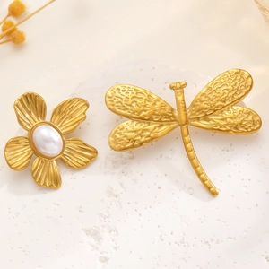 Macro shot of vintage gold flower and dragonfly brooches with pearl detail on a stone tray