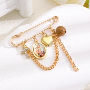 Nahaufnahme der goldenen Sicherheitsnadel-Brosche mit religiöser Medaille und Kreuz