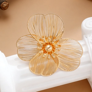 Macro shot of gold hollow petal flower brooch on a white decorative pedestal base