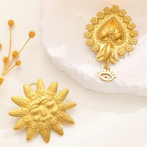Macro detail of vintage gold celestial sun and sacred heart eye brooches on stone