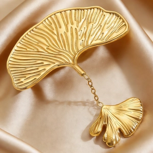 Macro view of golden ginkgo leaf brooch with fine veins on champagne satin fabric