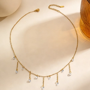 Detail van gouden kwastjesketting met fonkelende heldere hartvormige zirkoonkristallen