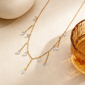 Detail van gouden kwastjesketting met fonkelende ronde zirkoonhangers aan een fijne ketting