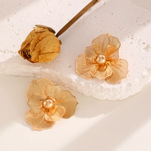 Detailed close-up of golden hollowed flower earrings with layered petals and a center bead