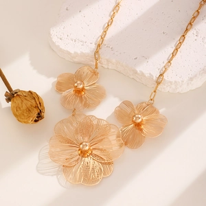 Luxurious gold flower necklace with intricate textured petals on white marble stone
