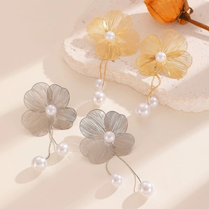 Detail of elegant wire-woven flower earrings with delicate pearls and gold tassels