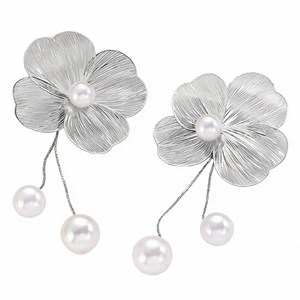 Detail of silver floral earrings featuring delicate petals and hanging pearl droplets