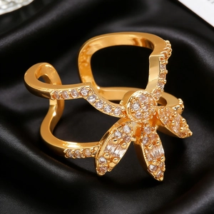 Macro shot of 18K gold wave ring with zircon flower on black silk background