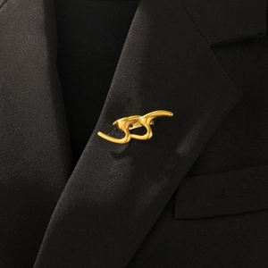 Broche aux lignes dorées abstraites sur revers noir pour un look de luxe élégant