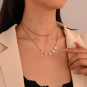 Close-up of gold layered necklace set featuring dainty daisy pendants on a female model