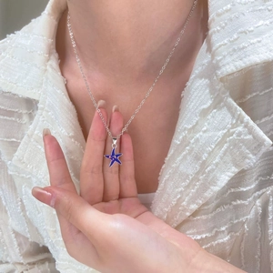 Close-up of a silver starfish necklace with blue sparkling inlay worn by a model