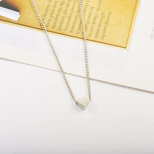 Détail macro du pendentif cœur argenté minimaliste avec finition miroir sur chaîne fine