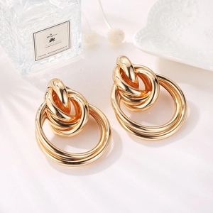 Detailed macro shot of golden geometric interlocking earrings with polished mirror finish