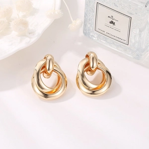 Macro detail of gold intertwined geometric knot earrings with polished finish