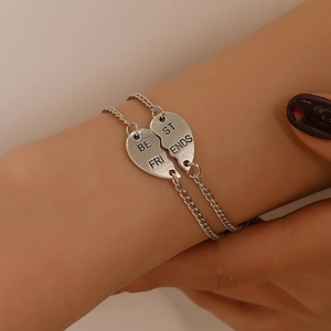 Detailed view of silver Best Friends heart pendants showing the engraved lettering details