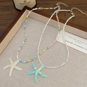 Detail van kleurrijke kralenkettingen met 3D-zeesterhangers in wit en cyaanblauw