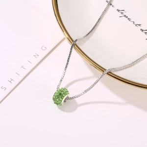 Macro shot of grass green crystal pave ball pendant on silver box chain necklace