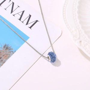 Macro detail of silver Venetian chain with a blue crystal encrusted cylindrical pendant