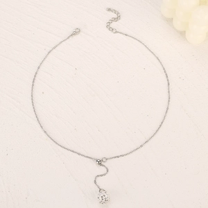 Silver Y-necklace with crystal-encrusted Shamballa ball pendant on white textured surface