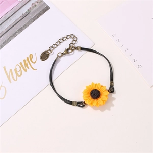 Detail view of sunflower bracelet with yellow charm, black cord, and bronze lobster clasp