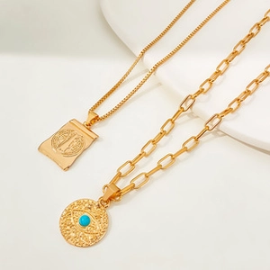 Détail de colliers dorés avec pendentif œil bleu et médaille de saint Benoît