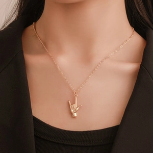 Détail d'un collier doré avec pendentif en forme de main porté par un mannequin
