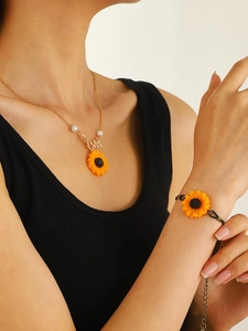 Detail of sunflower necklace and black woven bracelet set on model with dark top